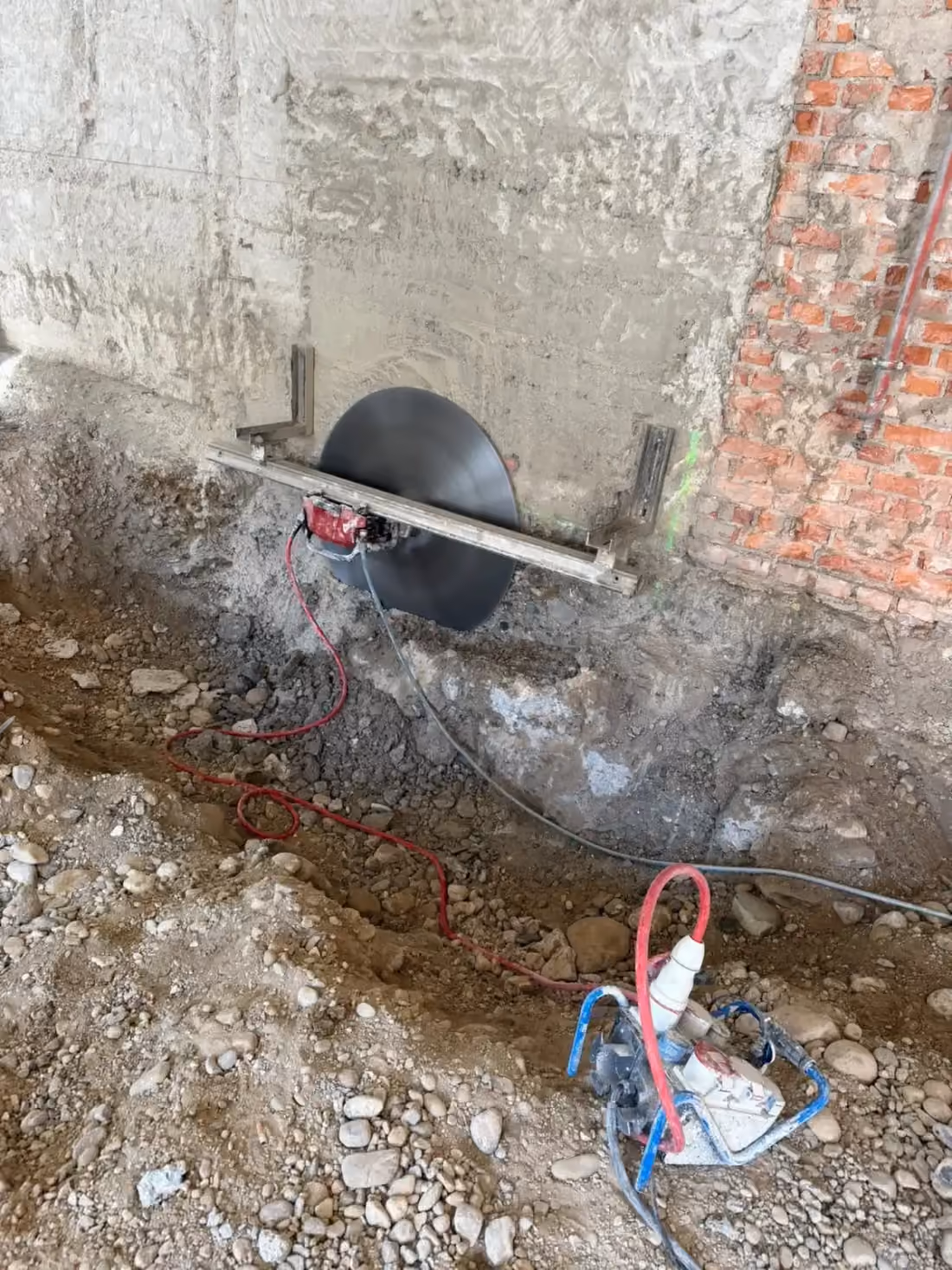 Große Sägescheibe an einer Wand aus Beton und Ziegel, davor Bauschutt